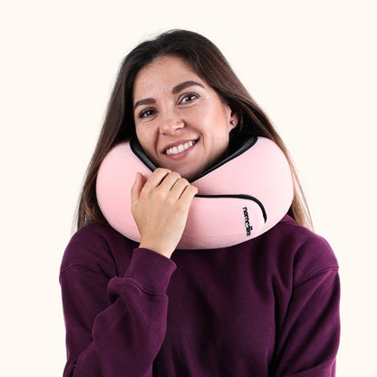 Woman holding a pink travel neck pillow against a white background